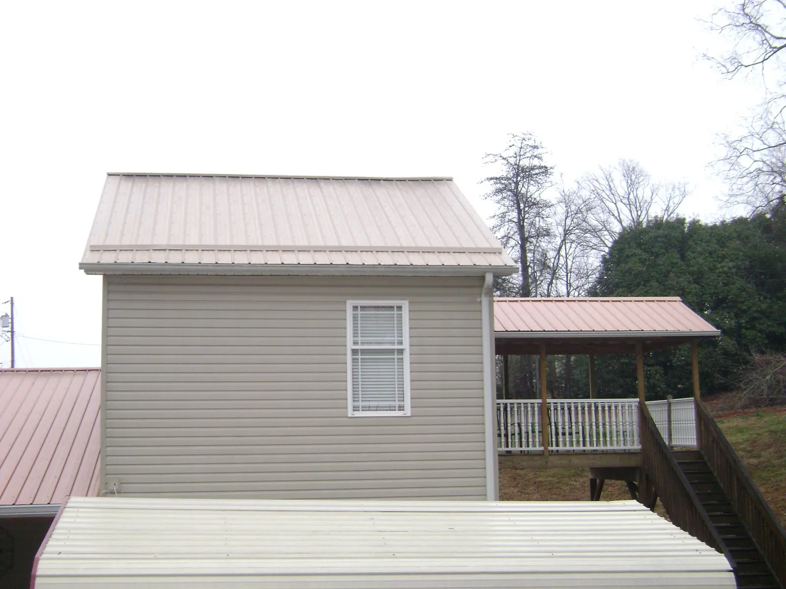 Tan metal roofs on a two story addition and attached porch, from a Roof Replacement job in Grandview
